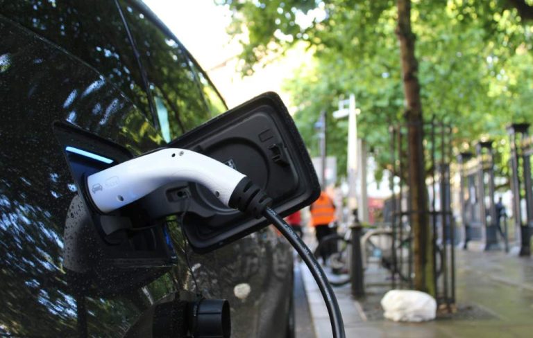 Electric car plugged in to charge on a city street