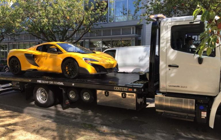 Yellow sports car on a flatbed tow truck